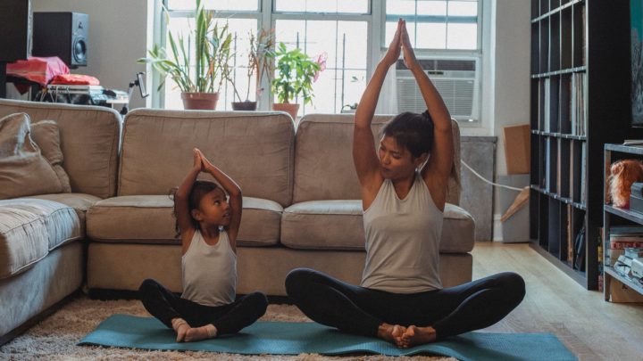 positive asian mother and daughter practicing yoga together at home